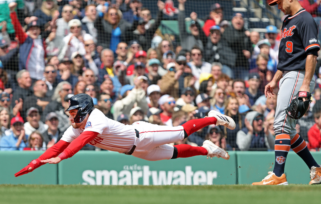 Boston Red Sox' Caleb Durbin dives headfirst into home plate as he scores on a second inning throwing error by Detriot Tigers' pitcher Jack Flaherrty, right, during a baseball game Monday, April 20, 2026 in Boston. (AP Photo/Jim Davis)