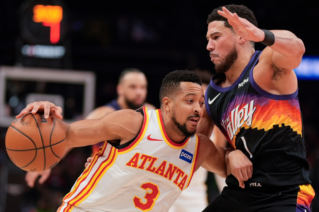 Atlanta Hawks guard CJ McCollum (3) drives against Phoenix Suns guard Devin Booker (1) during the first half of an NBA basketball game, Friday, Jan. 23, 2026, in Atlanta. (AP Photo/Mike Stewart)