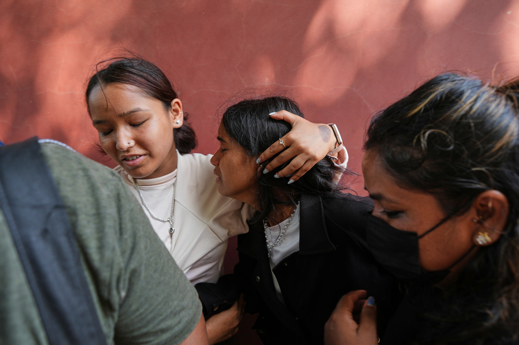 A relative consoles Jenisha, center, as she cries while waiting for the news of her father missing after flash flooding in Nepal's Nuwakot district, Friday, Aug. 28, 2026. (AP Photo/Rajesh Kumar Singh)