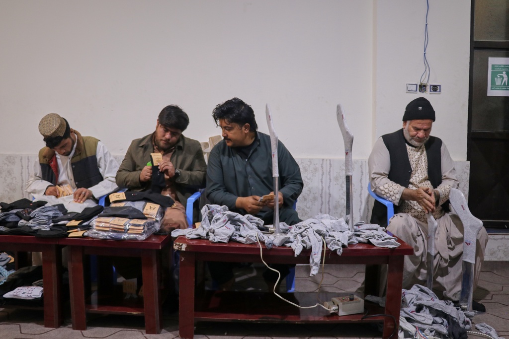 Local businessman Mohammad Amiri, 35, second from left, labels a pair of socks as he works with his staff, all of whom have disabilities, in his sock production workshop in Herat, western Afghanistan, Monday, Dec. 8, 2025.(AP Photo/Omid Haqjoo)