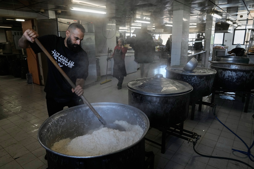 Volunteers cook meals for displaced people who fled Israeli airstrikes in southern Lebanon and Dahiyeh, Beirut's southern suburbs, at the Bir Hassan Technical Institute, which has been turned into a shelter, in Beirut, Lebanon, Wednesday, March 11, 2026. (AP Photo/Bilal Hussein)