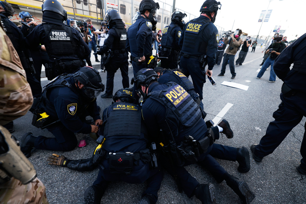 Police detain a protester near the Metropolitan Detention Center in downtown Los Angeles during a "No Kings" protest Saturday, March 28, 2026. (AP Photo/Jill Connelly)