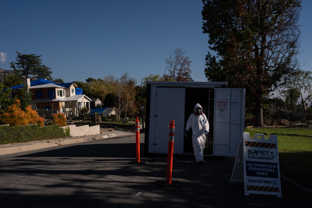 A worker in protective gear exits a storage container at a cleanup site, Dec. 3, 2025, months after the Eaton Fire, in Altadena, Calif. (AP Photo/Jae C. Hong)