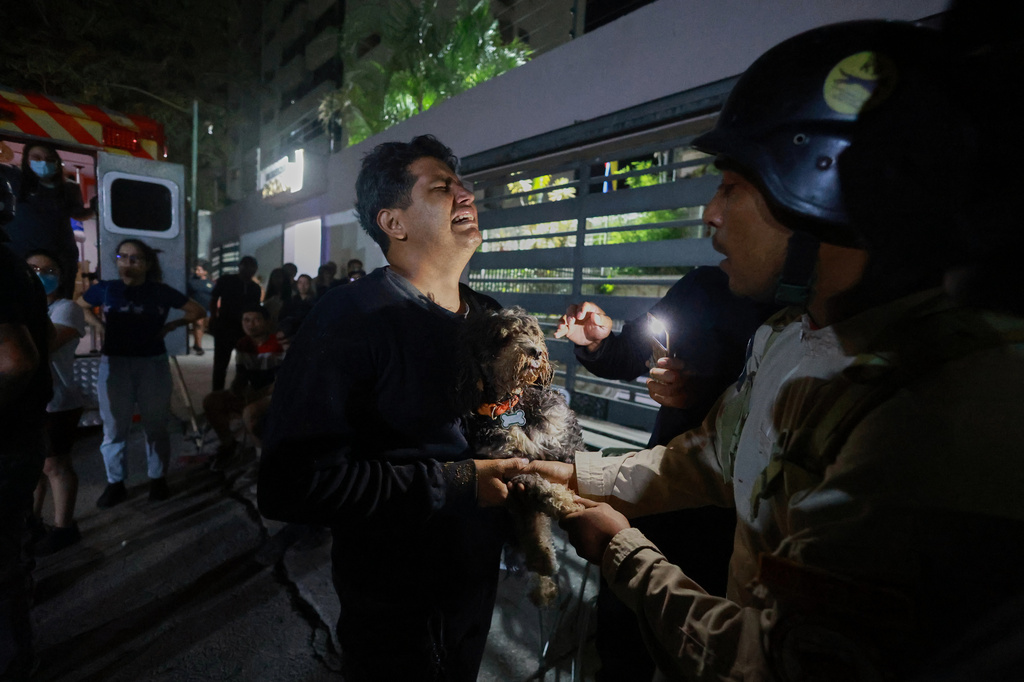 A man holding a dog cries after an earthquake in Caracas, Venezuela, Wednesday, June 24, 2026. (AP Photo/Javier Campos)