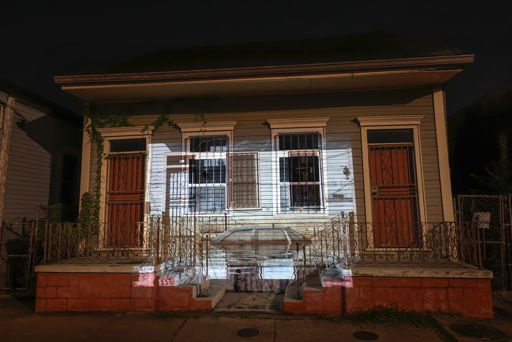 This photo of receding floodwaters leaving their mark on a house and automobile on Orleans Avenue in the aftermath of Hurricane Katrina in New Orleans, taken by AP photographer Ric Francis, is projected Wednesday, Aug. 20, 2025, onto the same house. (AP Photo/Gerald Herbert)