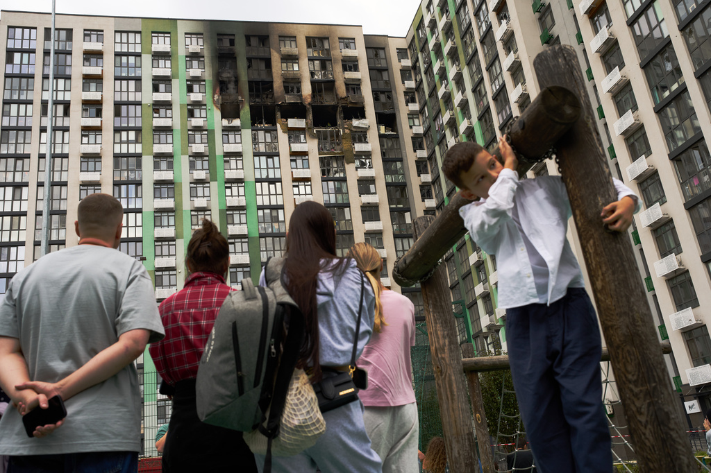 Locals watch as firefighters work after a Russian drone attack struck a residential building in Kyiv, Tuesday, Sept. 1, 2026. (AP Photo/Francisco Seco)