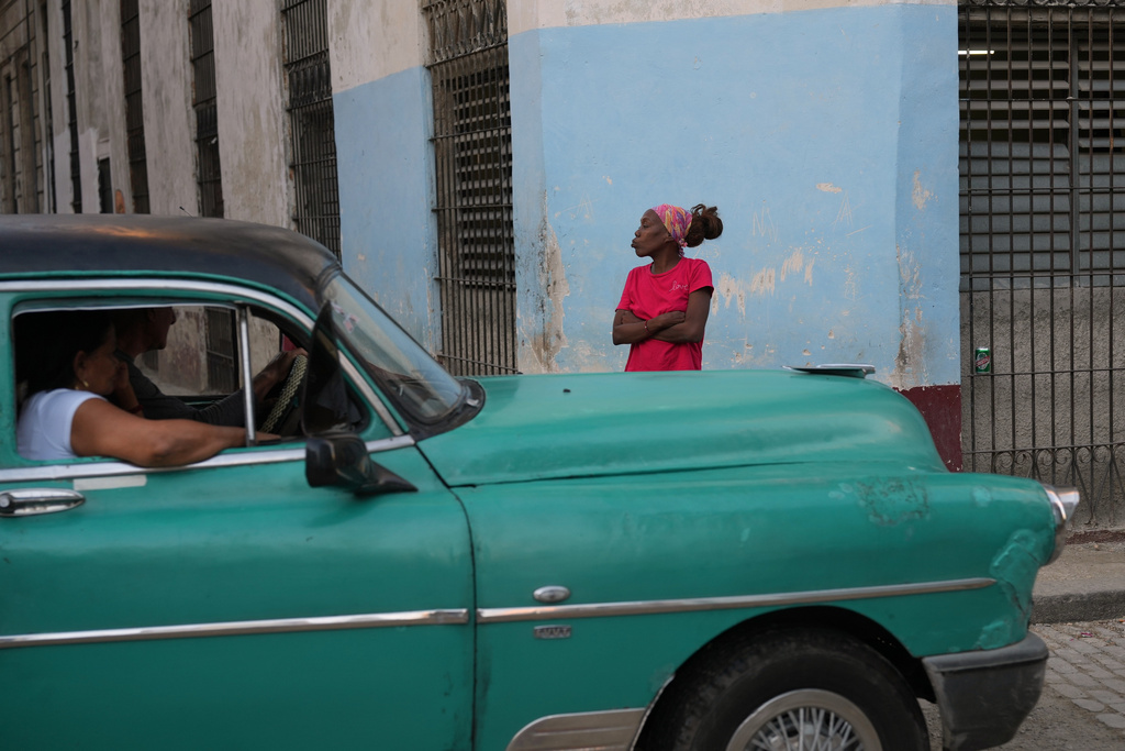A woman gestures next to a classic American car in Old Havana, Monday, January 5, 2026. (AP Photo/Ramon Espinosa)