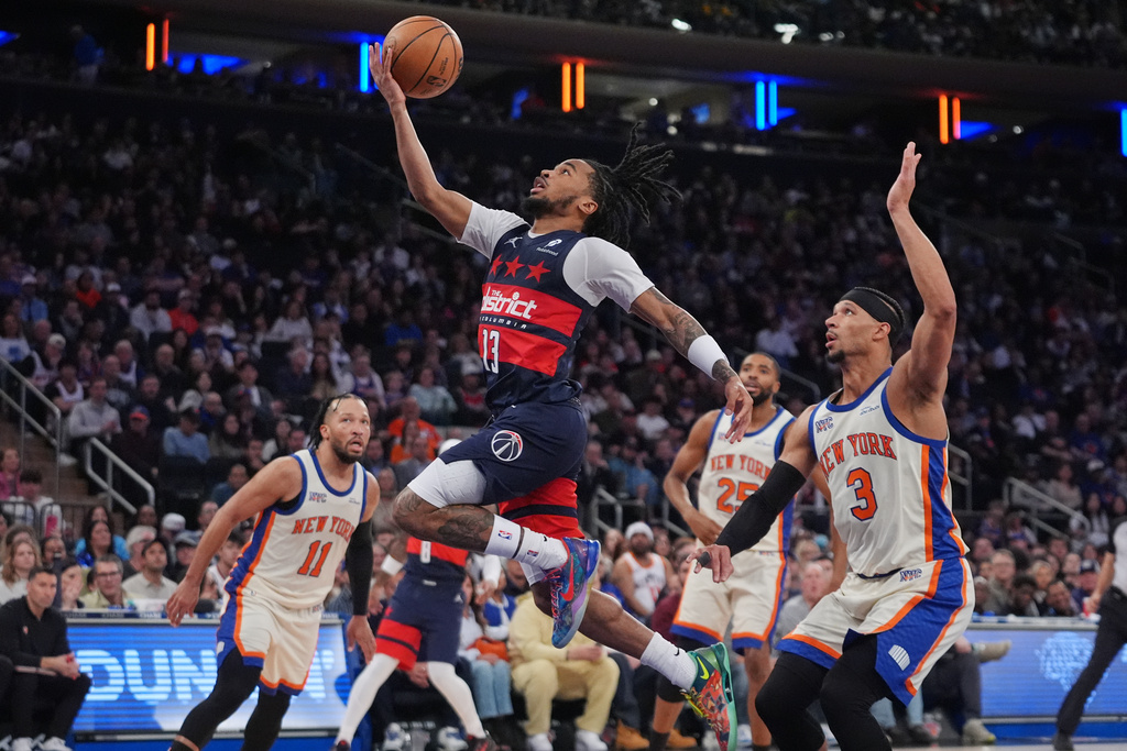 Washington Wizards' Sharife Cooper (13) drives past New York Knicks' Josh Hart (3) and Jalen Brunson (11) during the second half of an NBA basketball game Sunday, March 22, 2026, in New York. (AP Photo/Frank Franklin II)