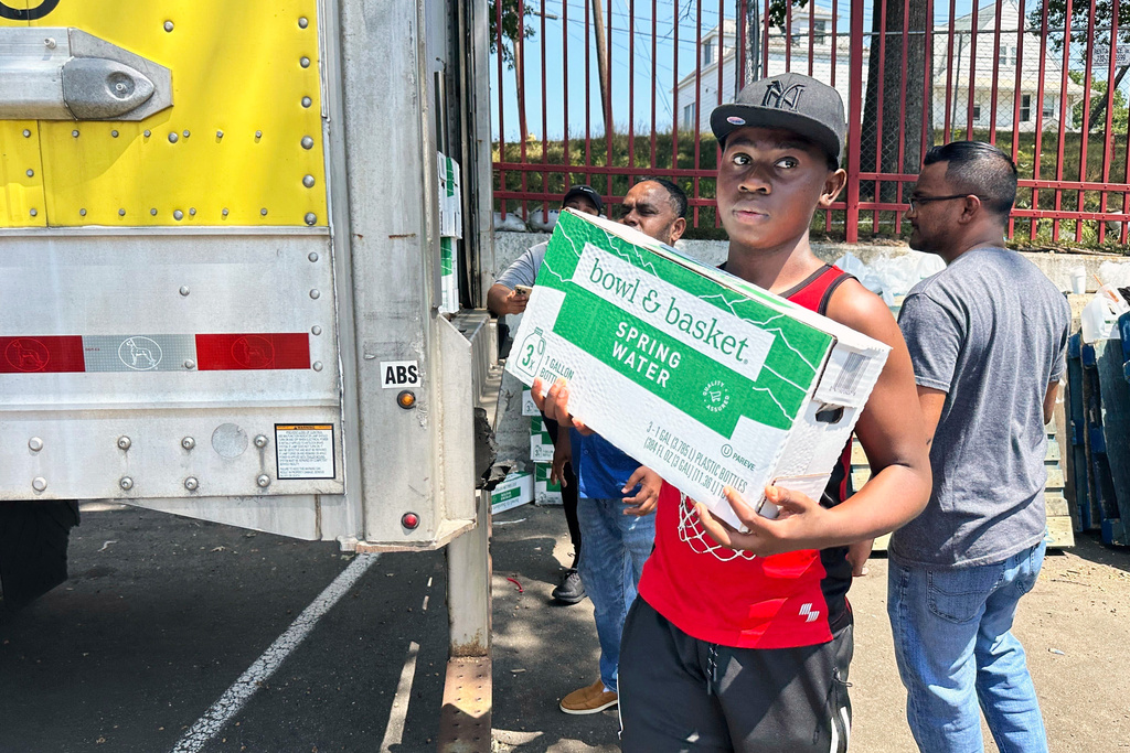 People, who were affected by a water main break that that led to reduced service to nearly 200,000 homes and businesses, pick up cases of bottled water at John F. Kennedy High School in Paterson, N.J., on Aug. 11, 2025. (AP Photo/Ted Shaffrey)