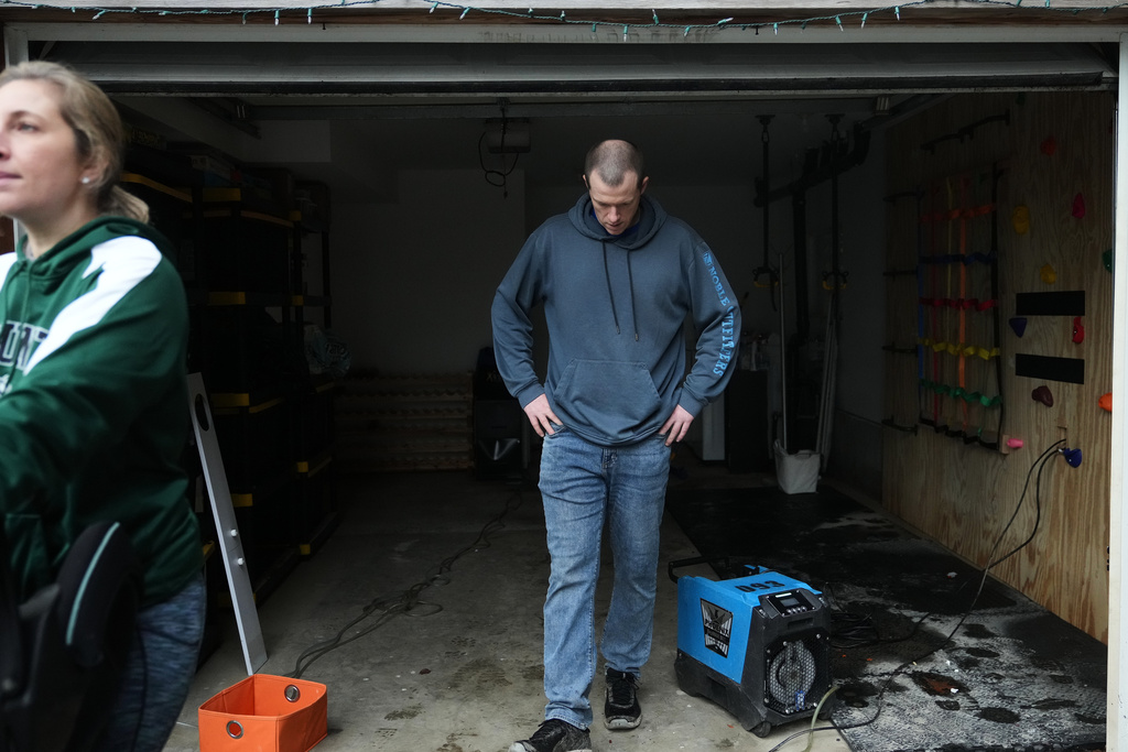 Todd Hinderman, right, and wife Marielle Hinderman, left, walk out of their garage after the lower level of their home flooded after heavy rains in the region Saturday, Dec. 13, 2025, in Burlington, Wash. (AP Photo/Lindsey Wasson)