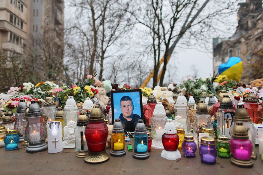 A photograph of a killed man stands among the lamps near a residential building which was heavily damaged by a Russian strike on Ternopil, Ukraine, Friday, Nov. 21, 2025. (AP Photo/Vlad Kravchuk)