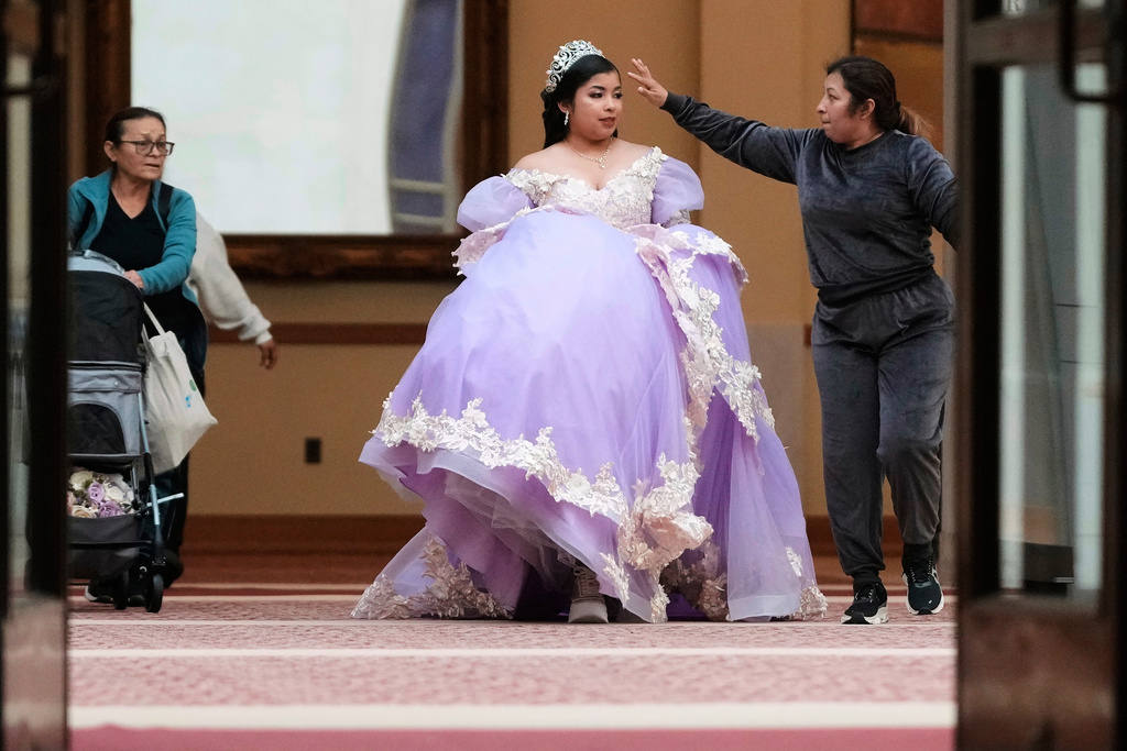 Leyla Portillo holds up her gown as she arrives to City Hall with her grandmother Olga Cetina, left, and mother Olga Portillo for her quinceañera portrait session in San Francisco, Monday, April 28, 2025. (AP Photo/Jeff Chiu)