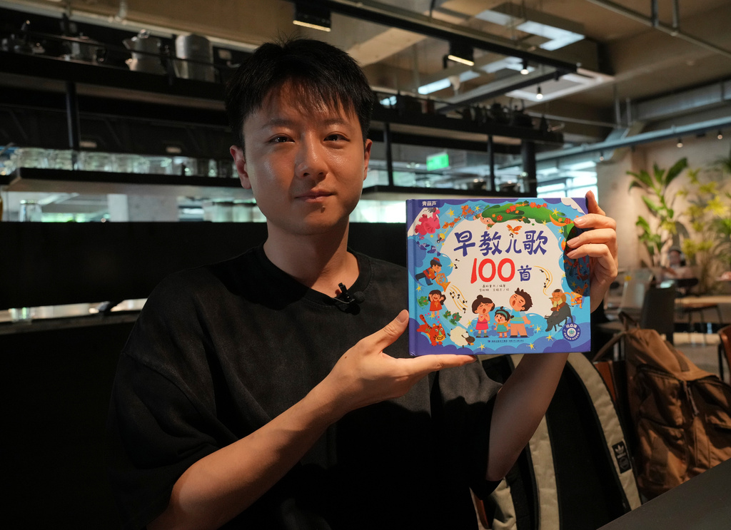 Wang Zhicheng hold his book at a coffee shop in Beijing on Tuesday, Aug. 4, 2026. (AP Photo/Achmad Ibrahim)