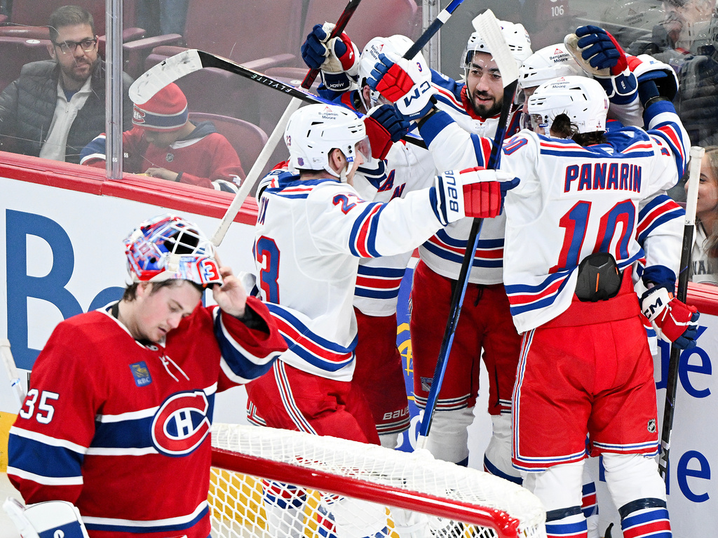 New York Rangers' J.T. Miller, second from right, celebrates with teammates after scoring against Montreal Canadiens goaltender Sam Montembeault (35) during the third period of an NHL hockey game in Montreal, Saturday, Oct. 18, 2025. (Graham Hughes/The Canadian Press via AP)