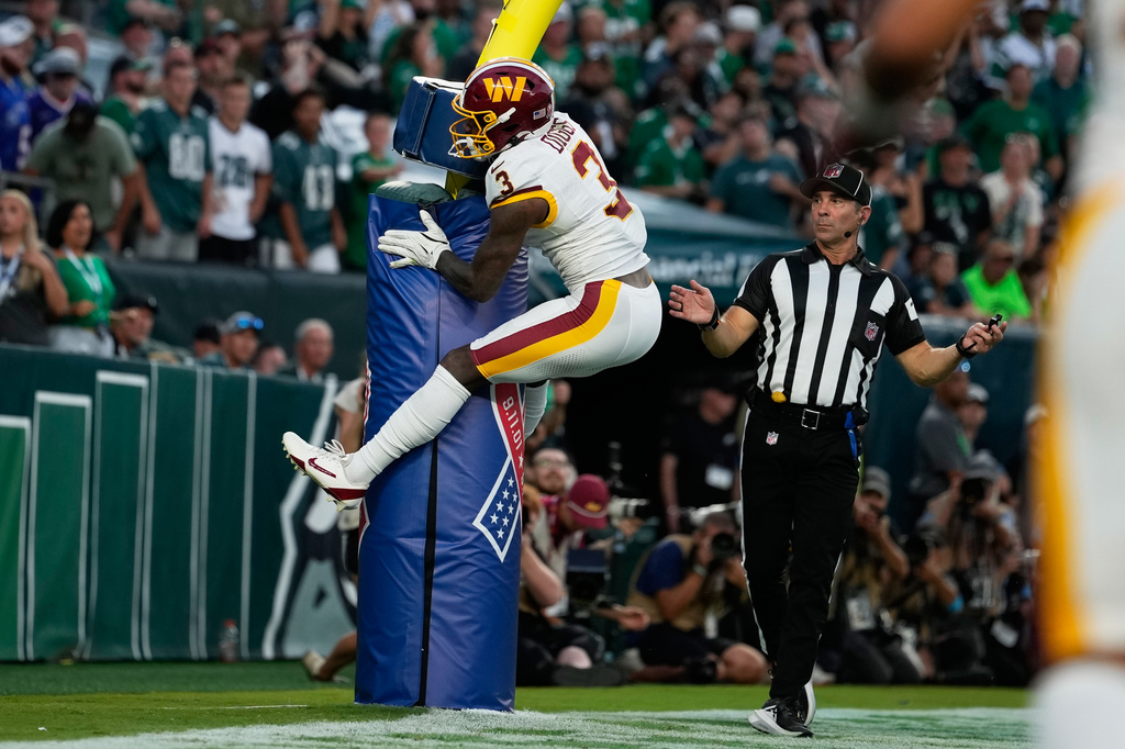 Washington Commanders wide receiver Stefon Diggs (3) jumps on the goal post as he celebrates his touchdown against the Philadelphia Eagles during the second half of an NFL football game, Sunday, Sept. 13, 2026, in Philadelphia. (AP Photo/Matt Slocum)