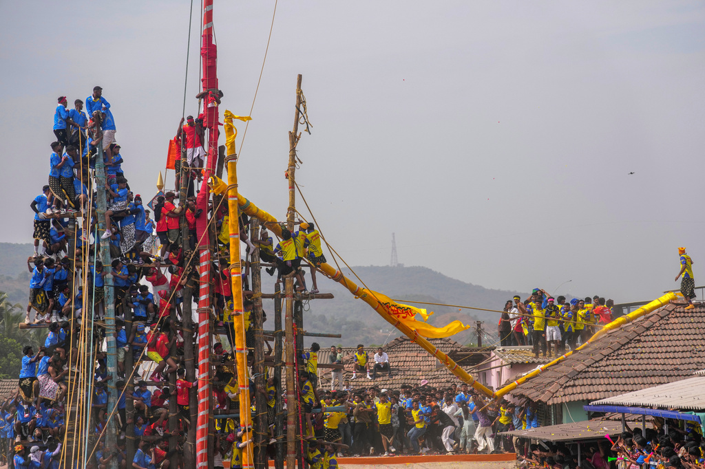 Onlookers step back as a decorated bamboo pole snaps moments after being raised by members of the Agri-Koli community as part of a centuries-old annual tradition honoring the local goddess Raiba Devi, in Rave village near Mumbai, India, Friday, April 17, 2026. (AP Photo/Rafiq Maqbool)