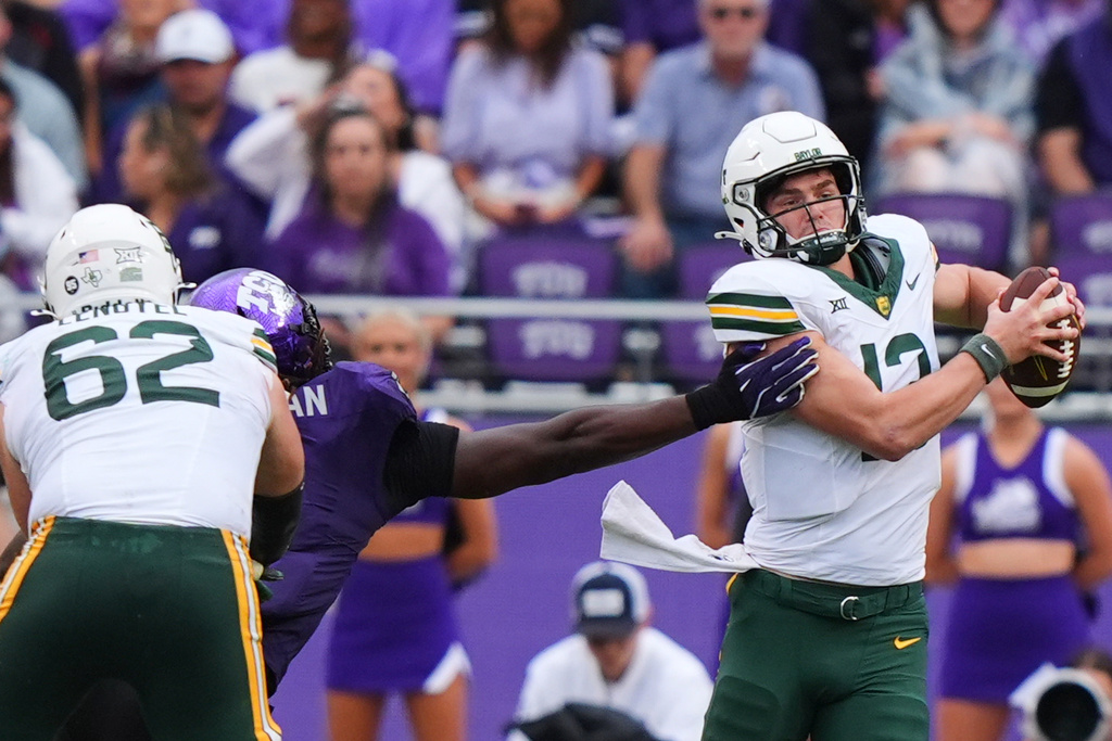 Baylor quarterback Sawyer Robertson (13) evades TCU defensive lineman Zachary Chapman as offensive lineman Ryan Lengyel (62) blocks during the first half of an NCAA college football game, Saturday, Oct. 18, 2025, in Fort Worth, Texas. (AP Photo/LM Otero)