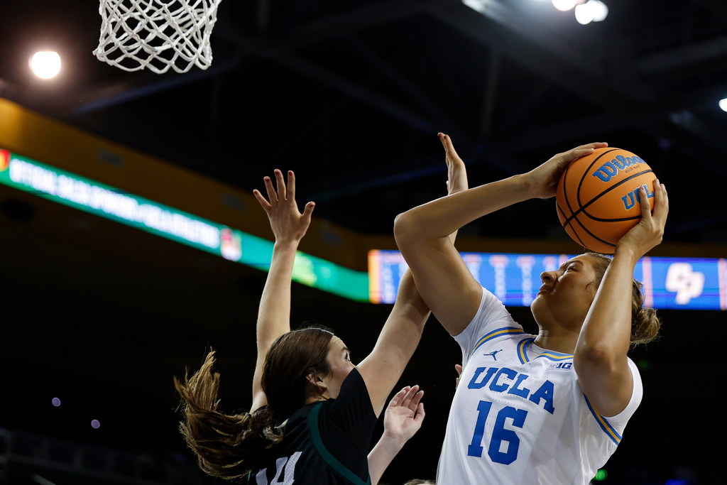 UCLA forward Sienna Betts (16) drives to the basket with the ball while being guarded by Cal Poly forward Gillian Bears (14) during the second half of an NCAA college basketball game Tuesday, Dec. 16, 2025, in Los Angeles. (AP Photo/Caroline Brehman)