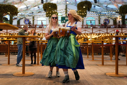 Waitresses celebrate in a beer tent after the re-opening of the Oktoberfest watched by police officers that was closed since the morning after a bomb threatening in Munich, Germany, Wednesday, Oct.1, 2025. (AP Photo/Matthias Schrader) Waitresses celebrate in a beer tent after the re-opening of the Oktoberfest watched by police officers that was closed since the morning after a bomb threatening in Munich, Germany, Wednesday, Oct.1, 2025. (AP Photo/Matthias Schrader)