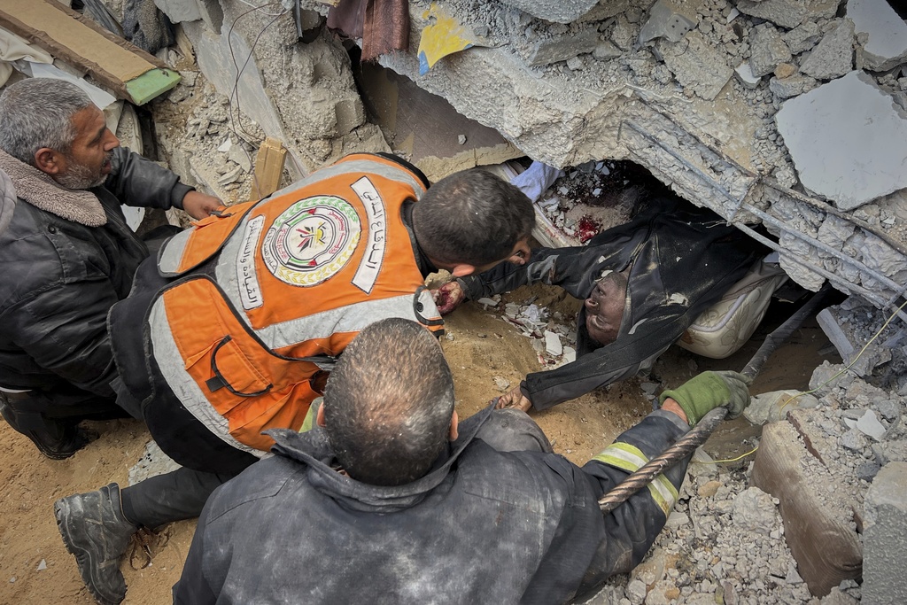 FILE - EDS NOTE: GRAPHIC CONTENT - Rescue workers and volunteers attempt to pull the body of a man from the rubble following an Israeli army airstrike in Khan Younis, southern Gaza Strip, Thursday, March 20, 2025. (AP Photo/Mariam Dagga, File)