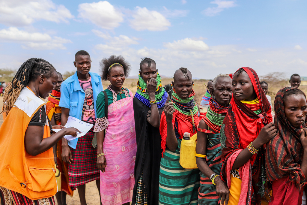 World Vision Kenya humanitarian worker verifies food assistance details as people queue for aid as prolonged drought continues in Nalemkais Village, Turkana County, Kenya, Sunday, Feb. 8, 2026. (AP Photo/Patrick Ngugi)