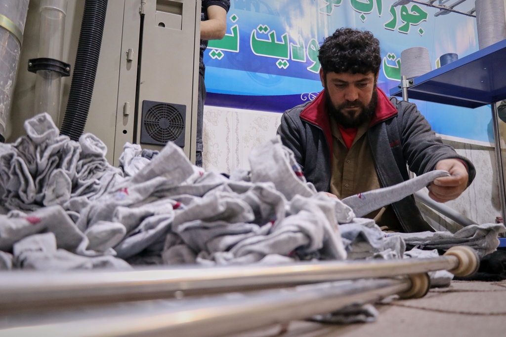 Shahabuddin, a double amputee since a roadside bomb took both his legs a decade ago, sorts freshly made socks to be packaged in a sock workshop staffed entirely by men with disabilities in the western Afghan city of Herat, Afghanistan, Monday, Dec. 8, 2025. (AP Photo/Omid Haqjoo)