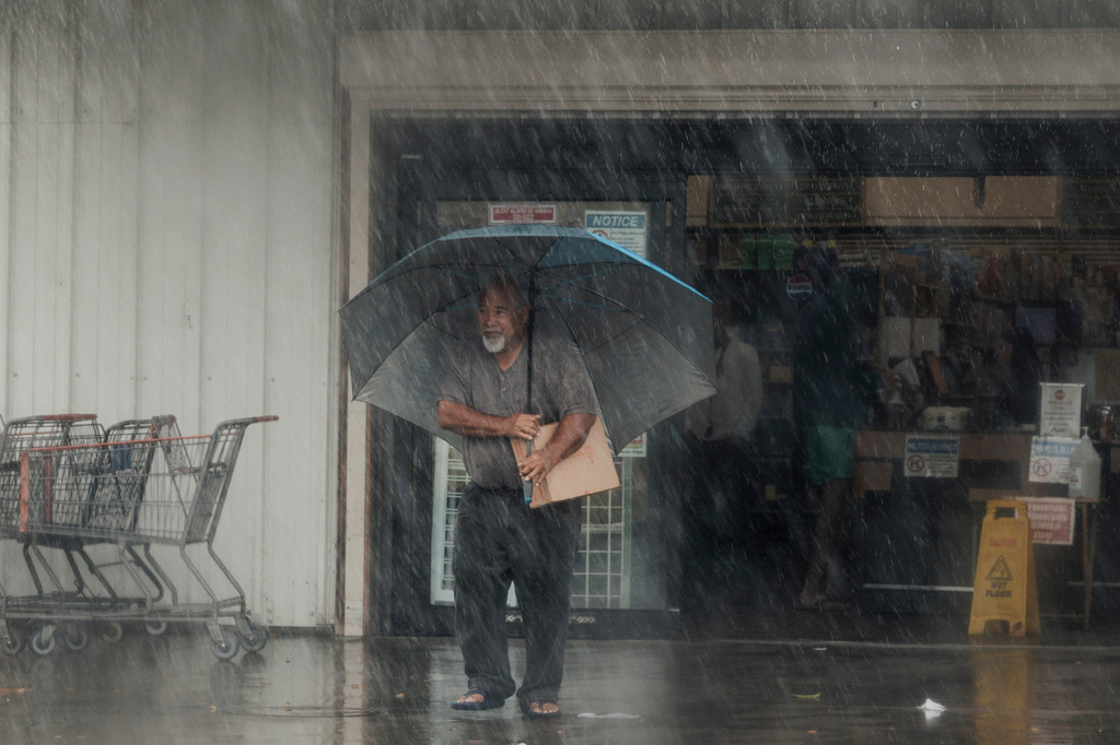 A resident carries supplies during Hurricane Lala in Hawaiian Ocean View, Hawaii, Saturday, Aug. 15, 2026. (Stephen Lam/San Francisco Chronicle via AP)