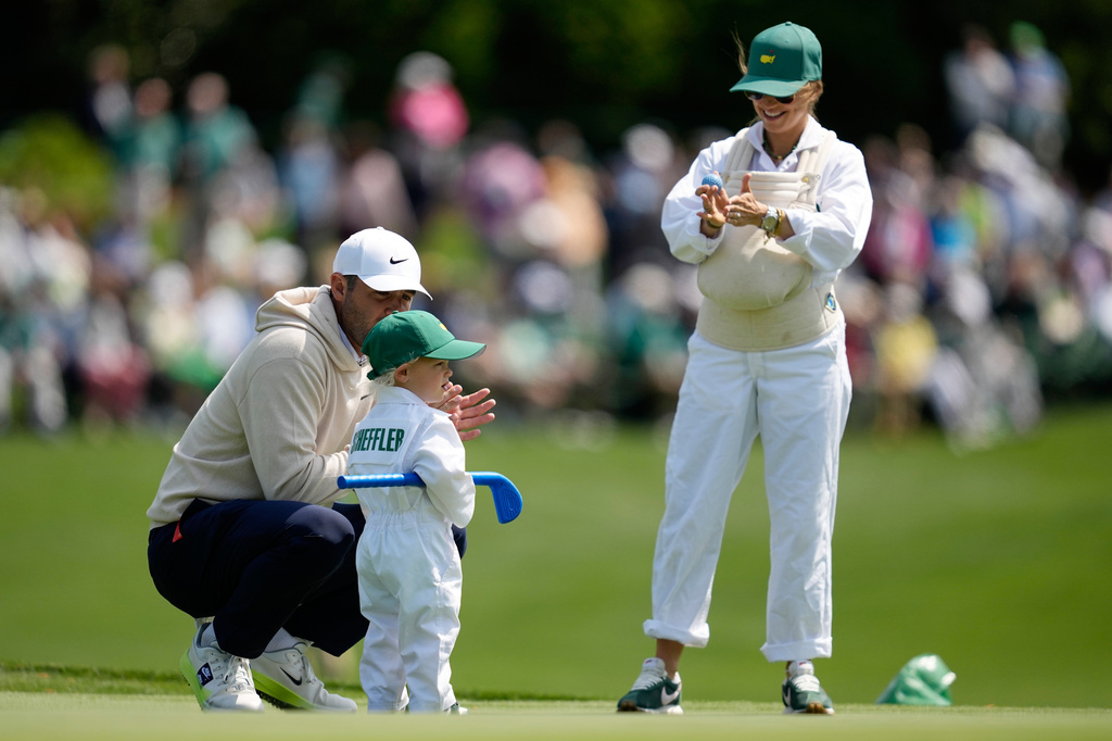 Scottie Scheffler, left, speaks with his son, Bennett, center, as his wife Meredith holds their son Remy, on the third hole during par-3 contest ahead of the Masters golf tournament at the Augusta National Golf Club, Wednesday, April 8, 2026, in Augusta, Ga. (AP Photo/Ashley Landis)