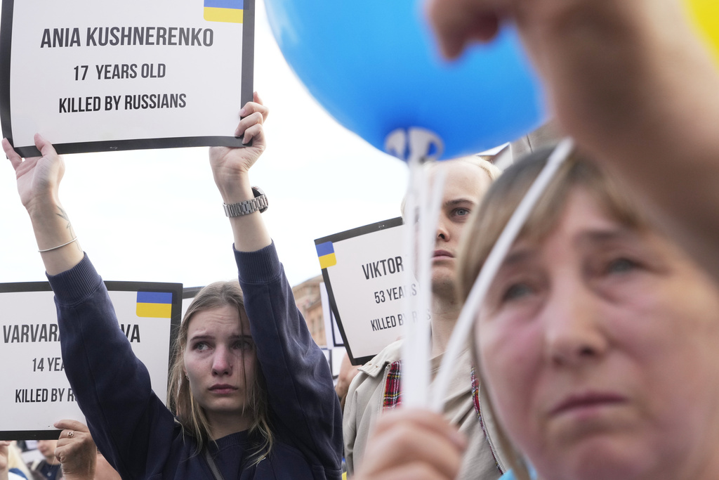 People hold signs at Warsaw's Castle Square to mark Ukraine's Independence Day in Warsaw, Poland, Sunday, Aug. 24, 2025. (AP Photo/Czarek Sokolowski)