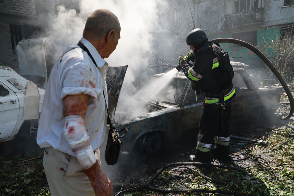 Rescue workers try to put out a fire of a residential building and cars burning after a Russian air guided bomb strike in Zaporizhzhia, Ukraine, Monday, Aug. 10, 2026. (AP Photo/Kateryna Klochko)