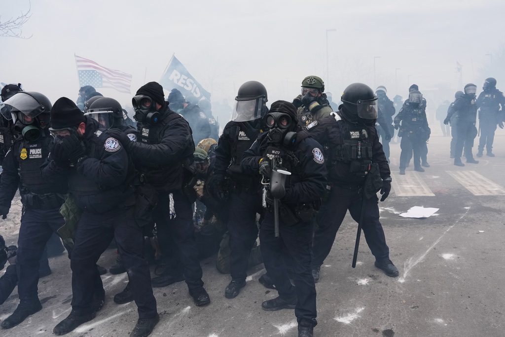 Federal immigration officers confront protesters outside Bishop Henry Whipple Federal Building, Thursday, Jan. 15, 2026, in Minneapolis. (AP Photo/Adam Gray)