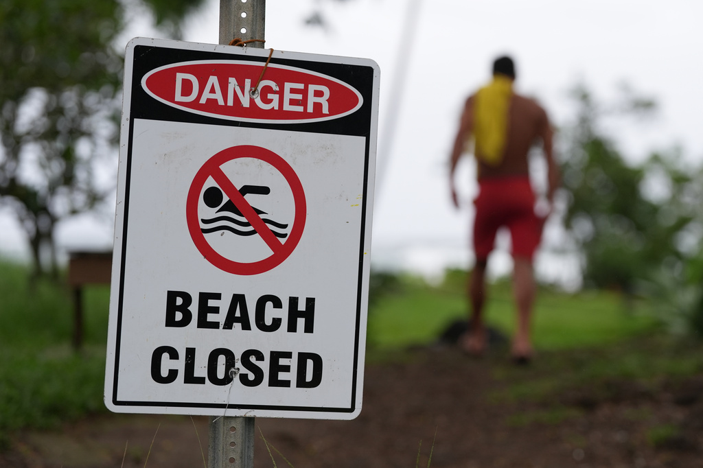 A lifeguard walks back to his tower after adjusting a beach closure sign as Hurricane Nolo sits nearby Saturday, Sept. 26, 2026, in Hilo, Hawaii. (AP Photo/Gregory Bull)