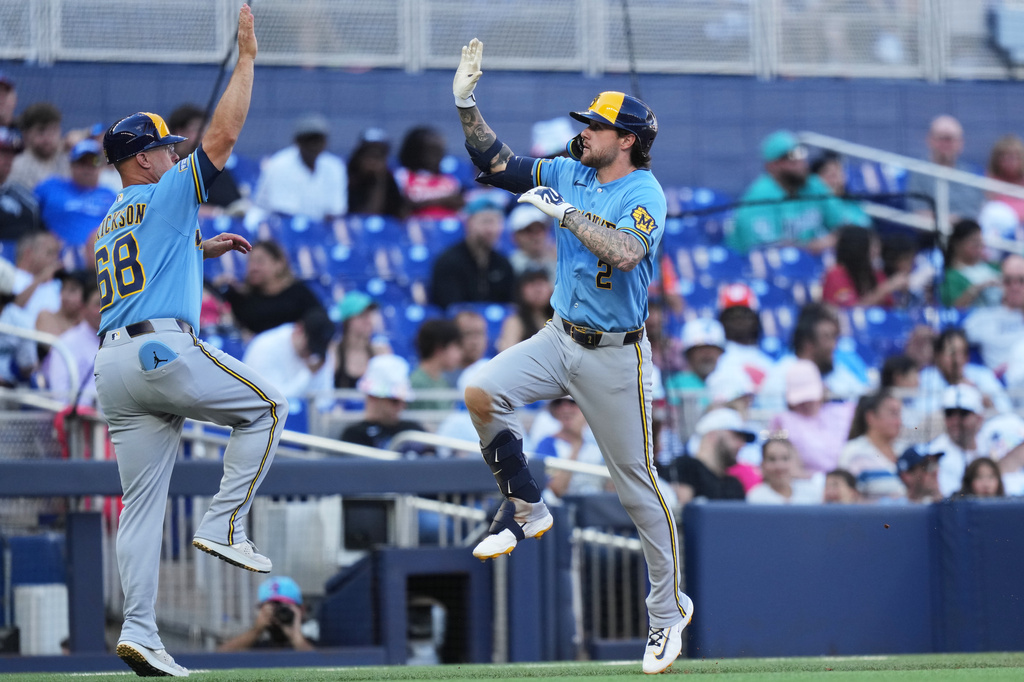 Milwaukee Brewers' Brice Turang (2) is met by third base coach Matt Erickson (68) after hitting a two-run home run during the fifth inning of a baseball game against the Miami Marlins, Saturday, April 18, 2026, in Miami. (AP Photo/Lynne Sladky)