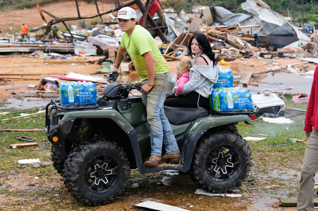 Mason Jones, left, and Heather Linton ride on a four-wheeler as they help residents at Gene's Mobile Home Supply, a trailer park in Bogue Chitto, Miss., Thursday, May, 7, 2026, after a tornado cut across the state. (AP Photo/Gerald Herbert)