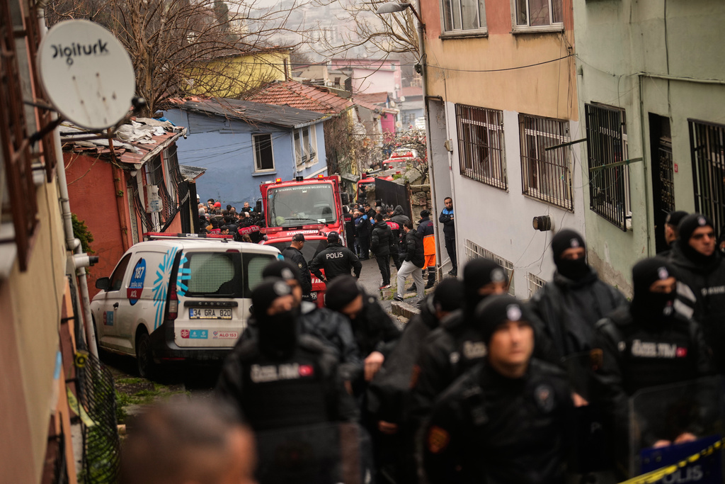 Police secure the way to a site where two residential buildings collapsed in Istanbul, Sunday, March 22, 2026. (AP Photo/Khalil Hamra)