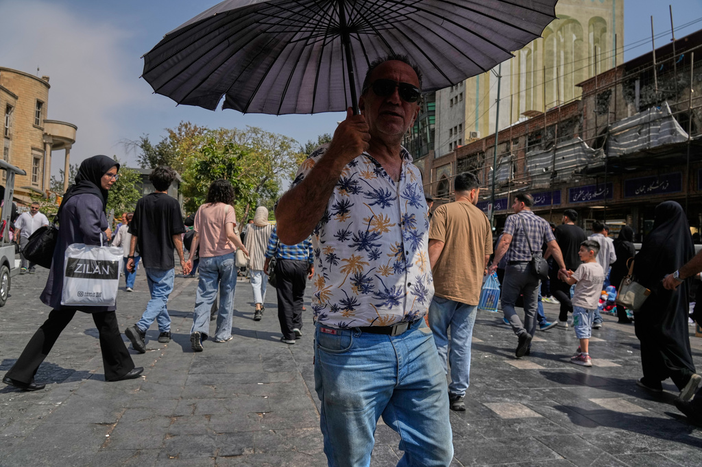 A man shelters from the sun under an umbrella around Tehran's traditional main bazaar, Iran, Saturday, Aug. 8, 2026. (AP Photo/Vahid Salemi)