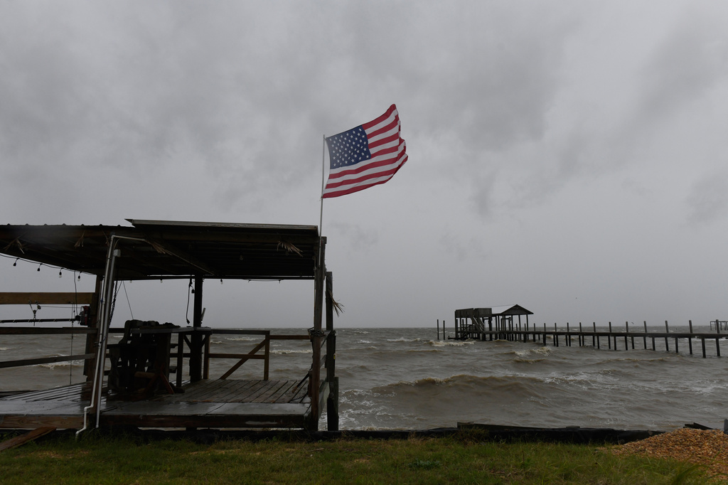 An American flag flaps in the wind generated by the effects of Isaias on an empty beach on Friday, Oct. 9, loom overhead on Friday, Oct. 9, 2026, in Mon Louis Island, Ala. (AP Photo/Octavio Jones)