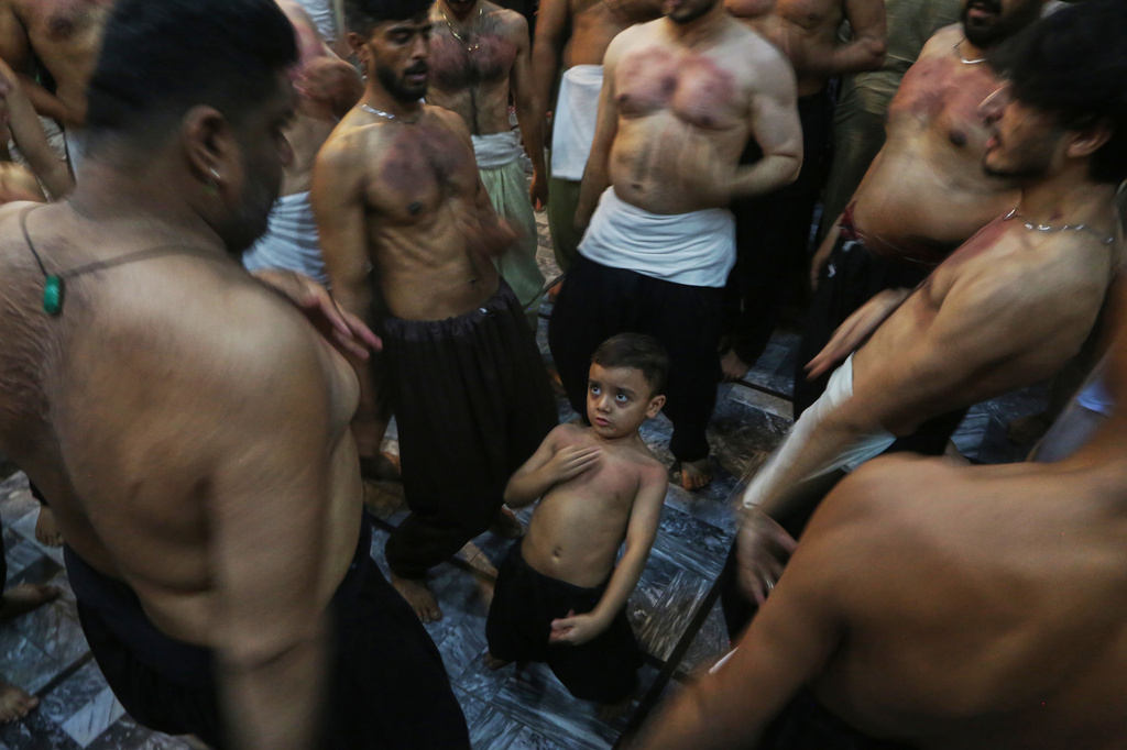 A Shiite Muslim boy beats his chest with others in a ritual during a gathering in the mourning month of Muharram, in Peshawar, Pakistan, late night on Sunday, June 21, 2026. (AP Photo/Muhammad Sajjad)