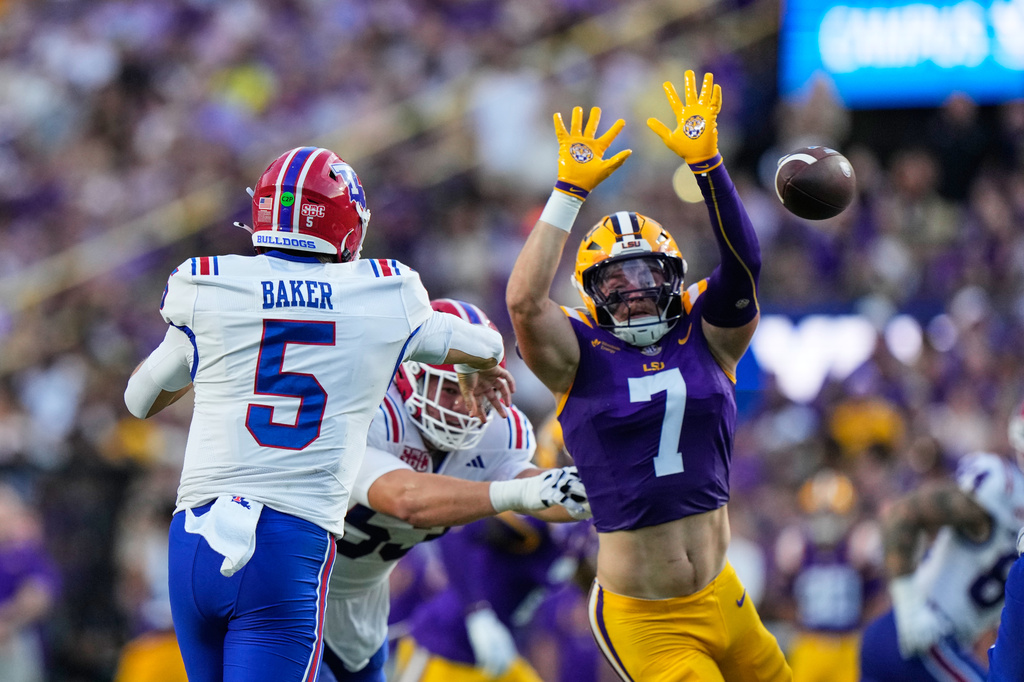 Louisiana Tech quarterback Blake Baker (5) passes under pressure from LSU linebacker Whit Weeks (7) in the first half of an NCAA college football game, Saturday, Sept. 12, 2026 in Baton Rouge, La. (AP Photo/Gerald Herbert)
