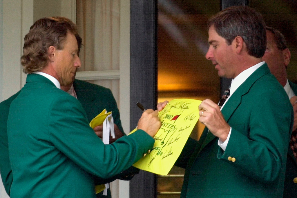 FILE - Former two-time Masters Champion Bernhard Langer, left, signs an autograph for fellow former champion Fred Couples, right, at the Augusta National Golf Club prior to the annual Champions dinner at the 2002 Masters, April 9, 2002, in Augusta, Ga. (AP Photo/Dave Martin, File)