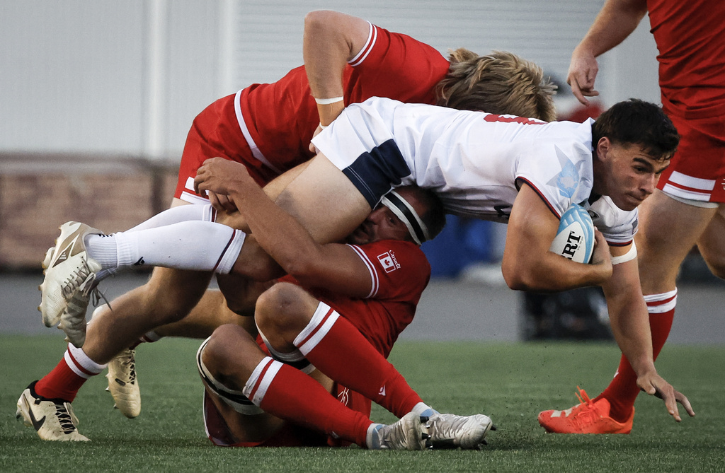 United States' Dominic Besag, front right, is tackled by Canada's Nic Benn and Tyler Ardron during second-half Pacific Nations Cup rugby match action in Calgary, Alberta, Friday, Aug. 22, 2025. (Jeff McIntosh/The Canadian Press via AP)