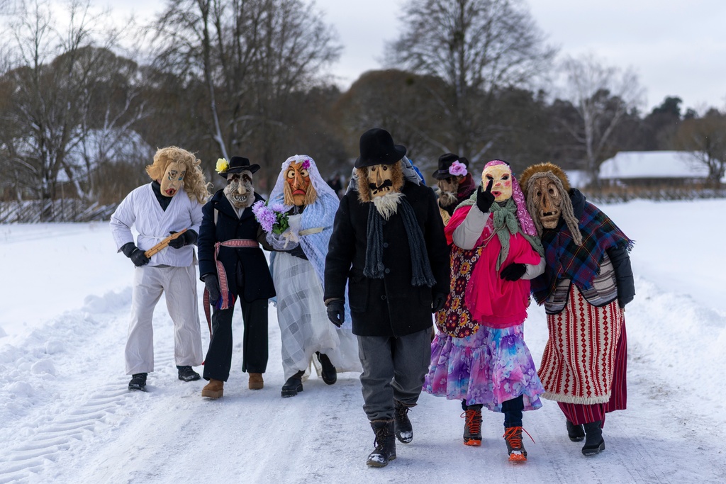 Revellers wearing traditional carnival masks take part in Shrovetide celebrations in the village of Rumsiskes, some 89 kilometers (56 miles) north of Vilnius, Lithuania, Saturday, Feb. 14, 2026. (AP Photo/Mindaugas Kulbis)