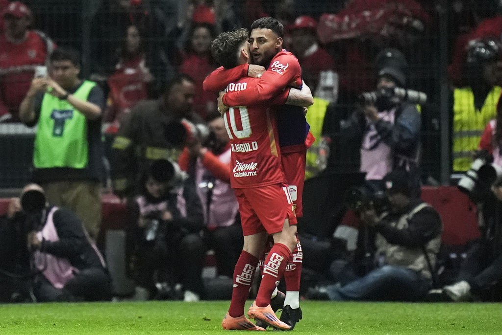 Toluca's Jesus Angulo, left, and Alexis Vega celebrate their side's second goal scored by Paulinho against Tigres during the Mexican soccer league second leg final match in Toluca, Mexico, Sunday, Dec. 14, 2025. (AP Photo/Eduardo Verdugo)