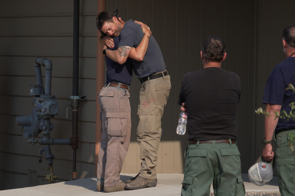 First responders hug during a procession in Grand Junction, Colo., Monday, June 29, 2026, for firefighters that died battling blazes near the Colorado-Utah border. (AP Photo/Ty ONeil)