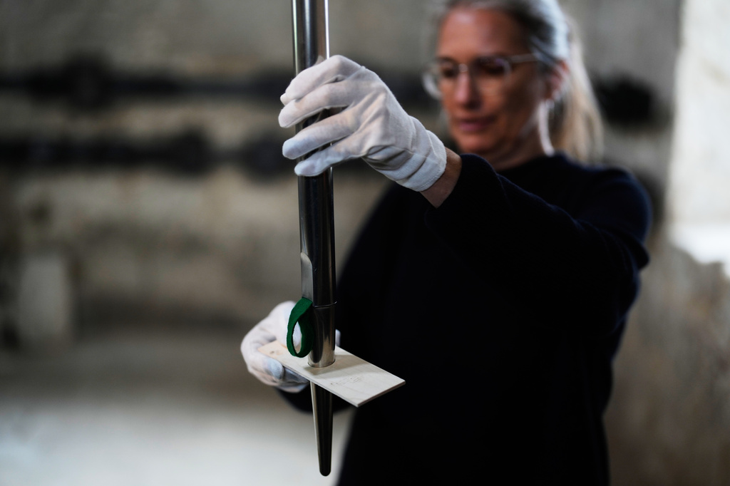 Curator Anneli Borgmann, chairwoman of the John Cage Organ Project Halberstadt's board of trustees, lifts a new pipe for a test at the John Cage organ project inside the Buchardi Church in Halberstadt, Germany, July 6, 2026. (AP Photo/Matthias Schrader)