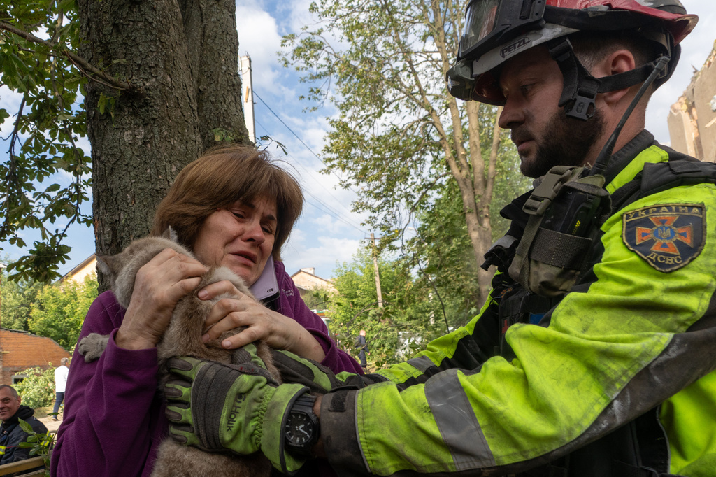 A firefighter gives a woman her cat that was found during search and rescue works in the damaged residential building following Russia's missile attack in Kharkiv, Ukraine, Saturday, June 20, 2026. (AP Photo/Andrii Marienko)
