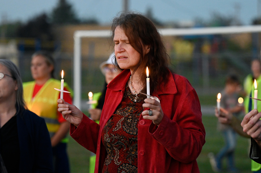 Attendees hold their lit candles during a vigil for a nearby church shooting held at Holy Redeemer Church in Burton, Mich., Sunday, Sept. 28, 2025. (AP Photo/Jose Juarez)
