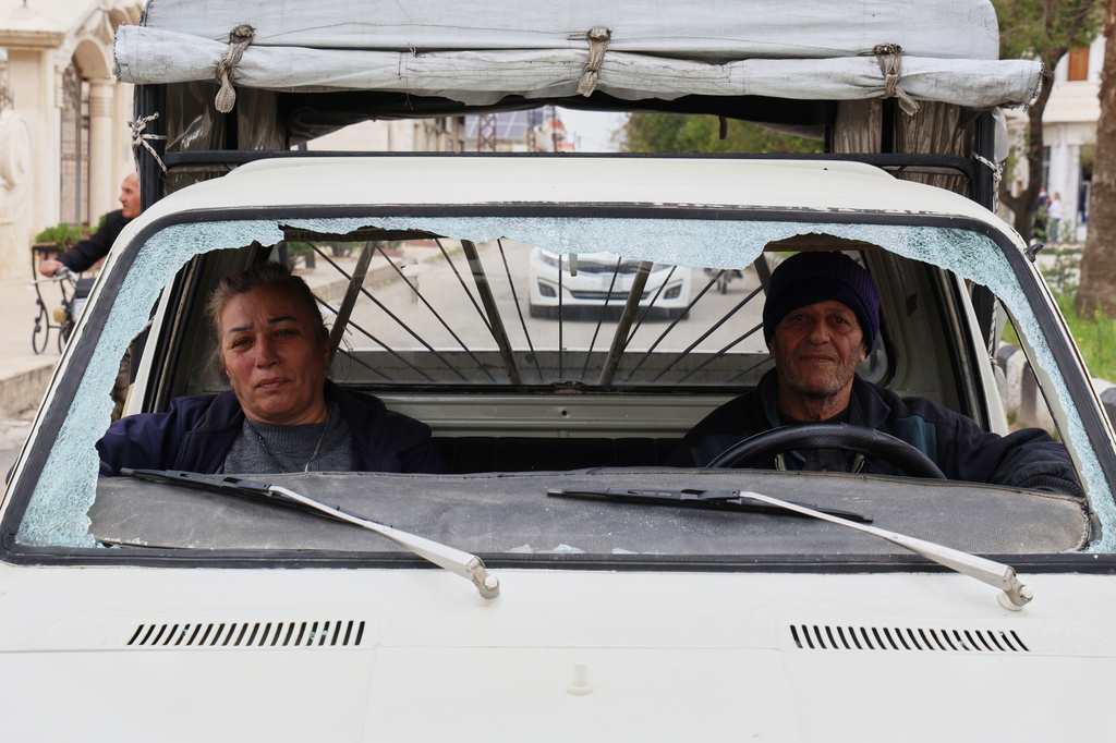 A man and a woman drive a vehicle with a shattered windshield in the predominantly Christian town of Al-Suqaylabiyah, west of Hama, Syria, Saturday, March 28, 2026, following overnight violence. (AP Photo/Omar Albam)