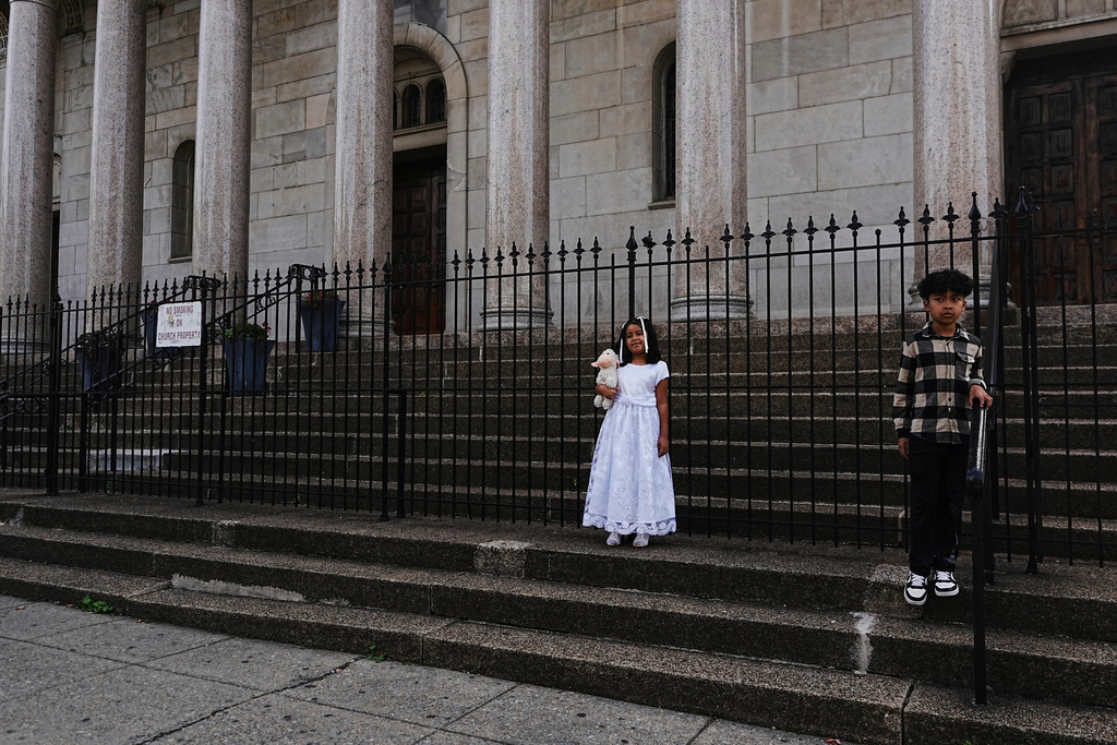 A girl stands outside the Shrine of the Sacred Heart after her baptism at the Catholic church in Washington, Oct. 11, 2025. (AP Photo/Luis Andres Henao)