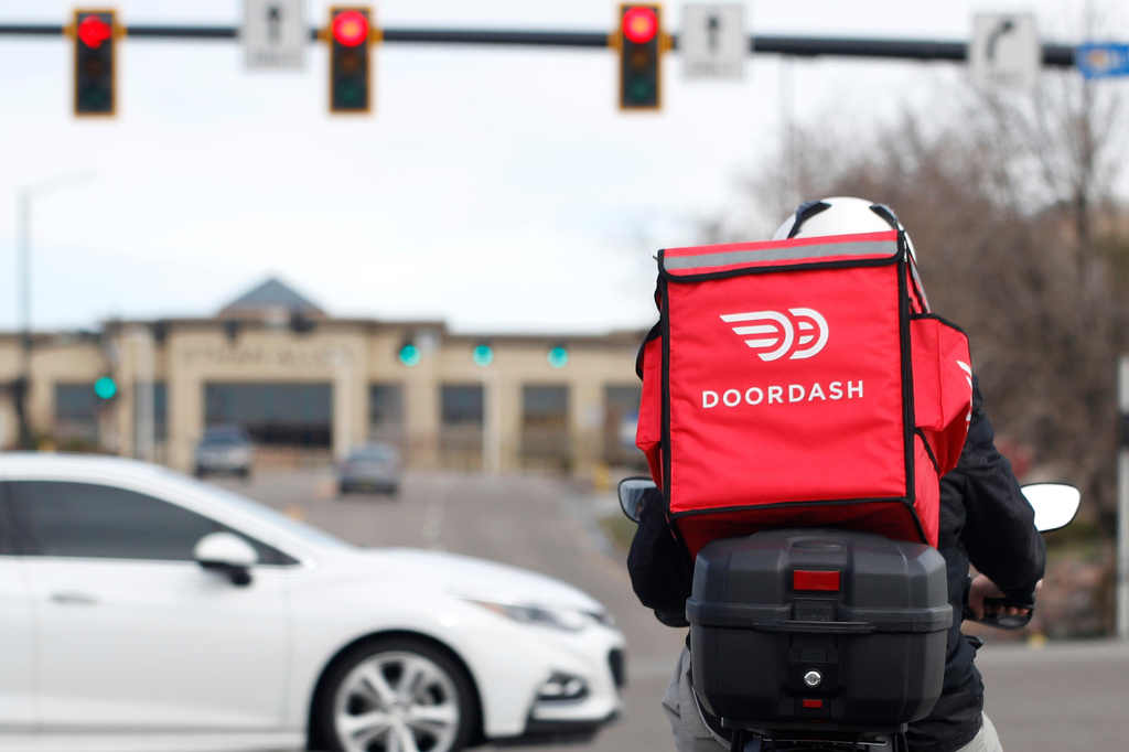 FILE - A food delivery rider waits at a traffic light, March 30, 2020, in Lone Tree, Colo. (AP Photo/David Zalubowski, File)